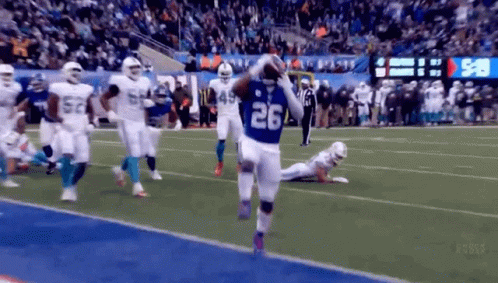 a football player wearing a number 26 jersey is running on the field .