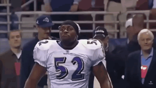 A Football Player Wearing A Number 52 Jersey Stands In Front Of A Crowd . GIF