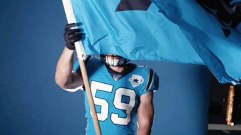 A Football Player Wearing A Number 59 Jersey Holds A Blue Flag GIF