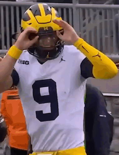 A Football Player Wearing A Number 9 Jersey Is Putting On His Helmet . GIF