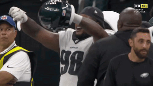 A Football Player Wearing A Number 98 Jersey Holds His Arms Up In The Air GIF