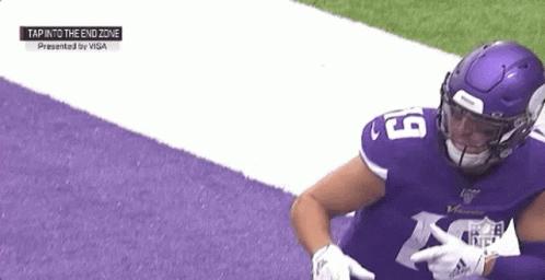 A Football Player Wearing A Purple Jersey And A Purple Helmet Is Sitting On The Field . GIF