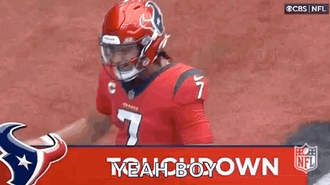 A Football Player Wearing A Red Helmet And A Red Jersey Is Standing In Front Of A Banner That Says Yeah Boy Down . GIF