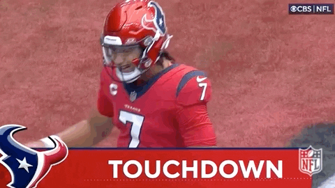 A Football Player Wearing A Red Helmet Is Standing On A Field With The Words `` Touchdown '' Behind Him . GIF
