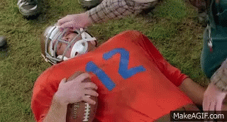 A Football Player Wearing A Red Jersey With The Number 12 On It Is Laying On The Ground . GIF