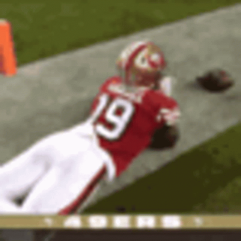 A Football Player Wearing A Red Jersey With The Number 19 On It Is Laying On The Field . GIF