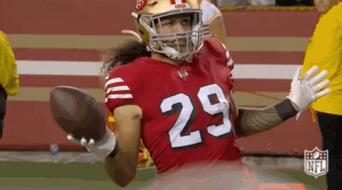 A Football Player Wearing A Red Jersey With The Number 29 On It Is Holding A Football In His Hand . GIF