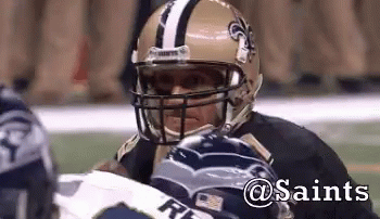 A Football Player Wearing A Saints Helmet Looks At Another Player GIF