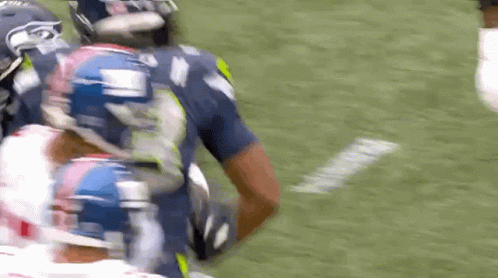 A Football Player Wearing A Seahawks Jersey Is Running With The Ball GIF