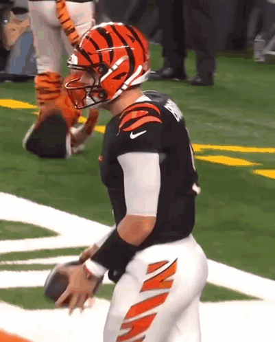 A Football Player Wearing A Tigers Helmet Is Holding A Football On The Field . GIF