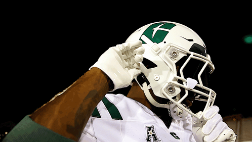 a football player wearing a white helmet with a green x on it