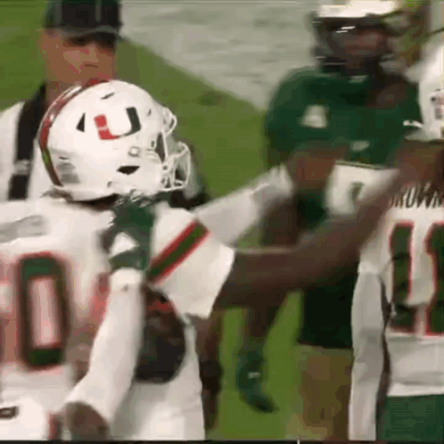 A Football Player Wearing A White Helmet With The Letter J On It Is Talking To Another Player On The Field . GIF