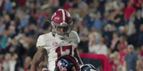 A Football Player Wearing A White Jersey With The Number 15 On It Is Running On The Field . GIF