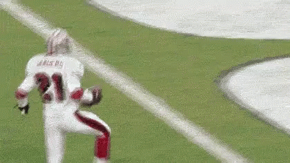 A Football Player Wearing A White Jersey With The Number 21 On It Is Running On The Field . GIF