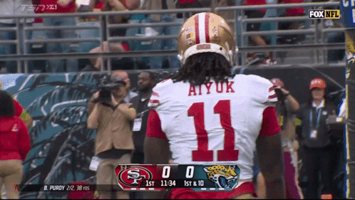 A Football Player Wearing Number 11 Stands In Front Of A Scoreboard GIF