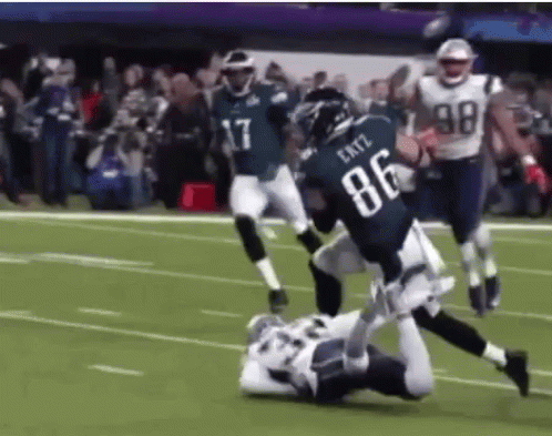 a football player wearing the number 86 is being tackled by another player