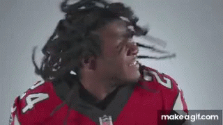 A Football Player With Dreadlocks Is Making A Funny Face While Wearing A Red Jersey . GIF