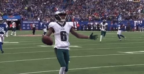 A Football Player With His Arms Outstretched Is Holding A Football On A Field . GIF