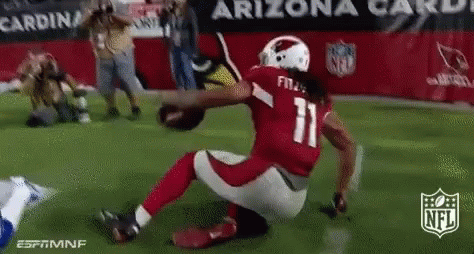 A Football Player With The Number 11 On His Jersey Is Kneeling On The Field While Holding A Football . GIF