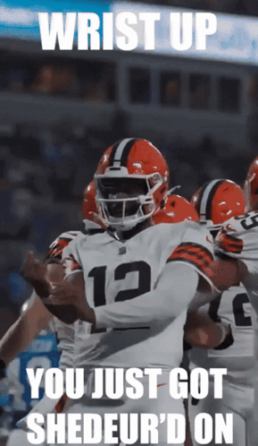 A Football Player With The Number 12 On His Jersey Is Surrounded By His Teammates GIF
