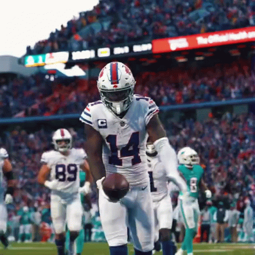 A Football Player With The Number 14 On His Jersey Is Holding A Ball GIF