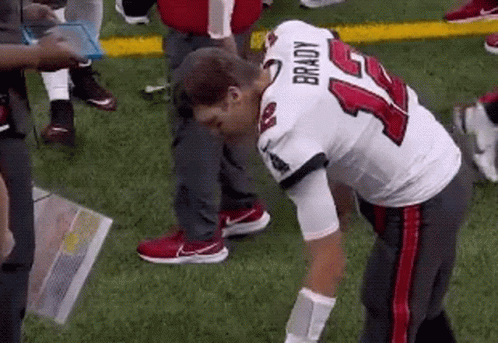 A Football Player With The Number 14 On His Jersey Is Kneeling Down On The Field . GIF