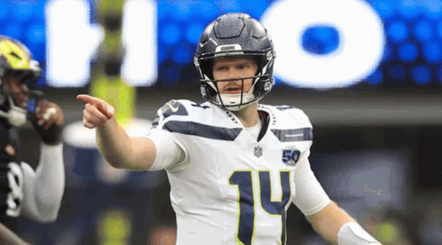 a football player with the number 14 on his jersey points at something