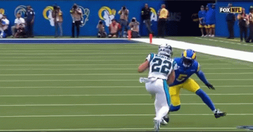 A Football Player With The Number 22 On His Jersey Is Being Tackled By Another Player On The Field . GIF