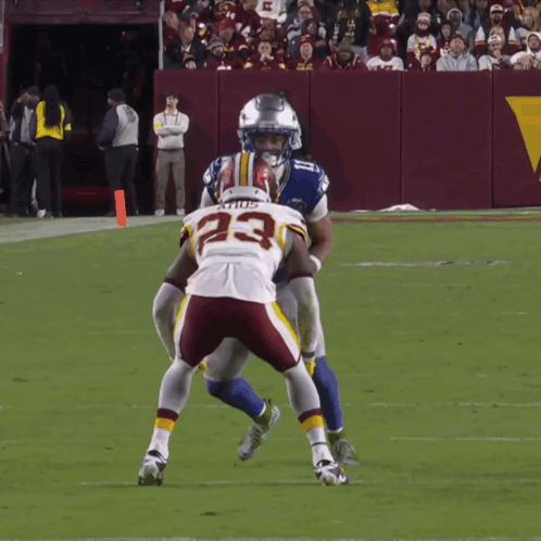 a football player with the number 23 on his jersey is being tackled by another player