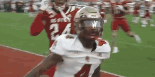 A Football Player With The Number 24 On His Jersey Is Being Tackled By Another Player On A Field . GIF