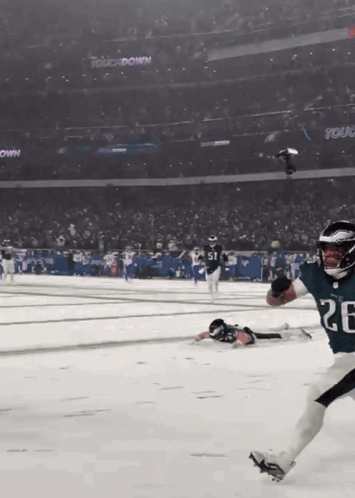 A Football Player With The Number 26 On His Jersey Is Running On A Snowy Field GIF