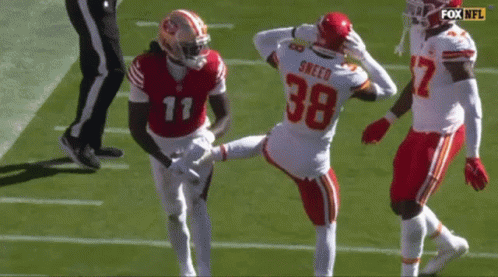 A Football Player With The Number 38 On His Jersey Is Kicking Another Player . GIF