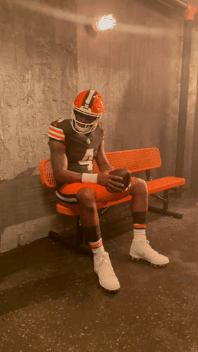 A Football Player With The Number 4 On His Jersey Sits On An Orange Bench GIF