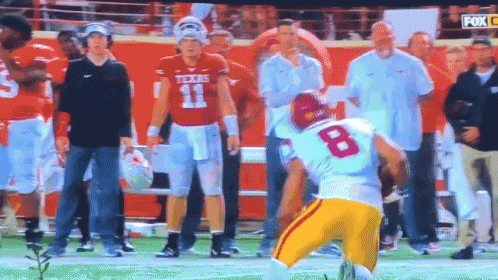 a football player with the number 8 on his jersey stands on the field