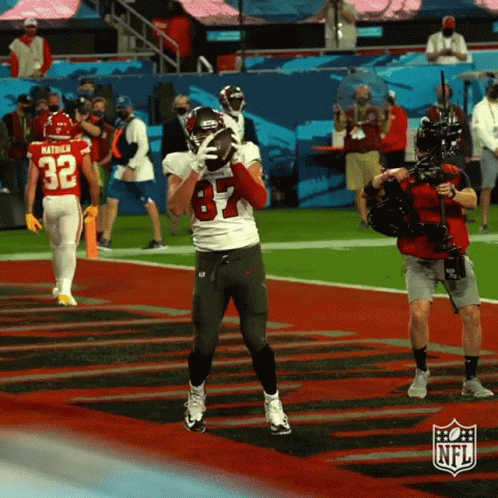 A Football Player With The Number 84 On His Jersey Is Holding A Football In His Hand GIF