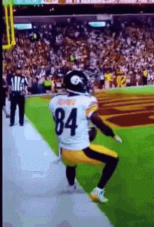 A Football Player With The Number 84 On His Jersey Is Squatting On The Field GIF