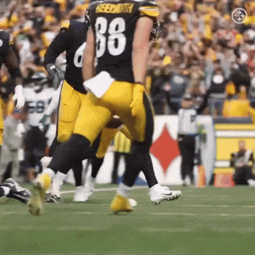 A Football Player With The Number 88 On His Jersey Is Running On A Field . GIF