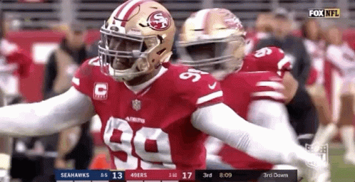 A Football Player With The Number 99 On His Jersey Is Being Hugged By Another Player . GIF