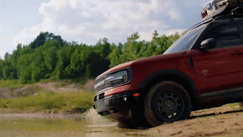 A Ford Bronco Is Driving Through A Muddy Area GIF