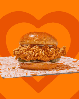 A Fried Chicken Sandwich With Pickles And Mayonnaise On A Bun GIF
