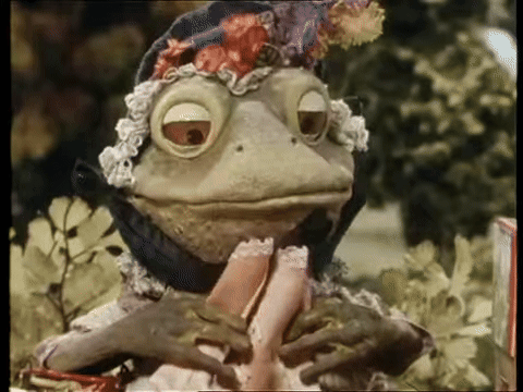 A Frog Wearing A Hat Is Holding A Woman 'S Leg GIF