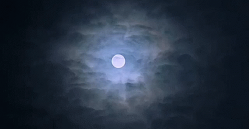 a full moon is visible through the clouds at night
