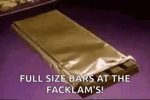 A Full Size Bar Of Chocolate Is Wrapped In Foil And Sitting On A Table . GIF