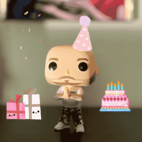 A Funko Pop Wearing A Party Hat Stands Next To A Birthday Cake And A Gift Box GIF