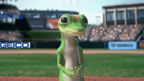 A Gecko Is Singing Into A Microphone At A Baseball Field GIF