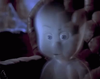 A Ghost Is Being Held In Someone 'S Hand In A Dark Room And Looking At The Camera . GIF