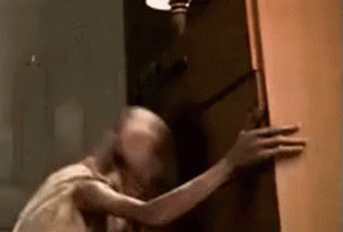 A Ghost Is Standing In A Doorway Holding A Door . GIF
