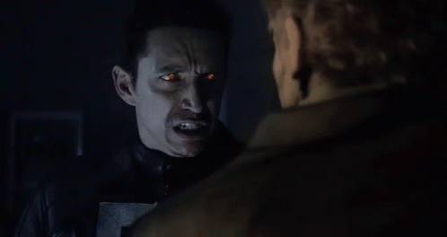 A Ghost Rider With Flames Coming Out Of His Head Is Standing Next To A Man . GIF