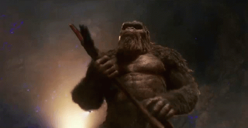 a giant gorilla is holding a sword in his hand in a dark room .