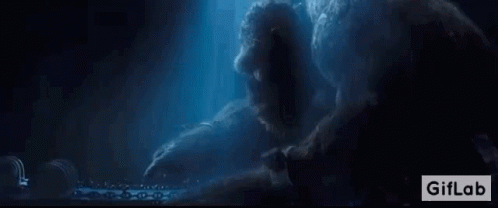 A Giant Monster Is Sitting On A Table In The Dark . GIF